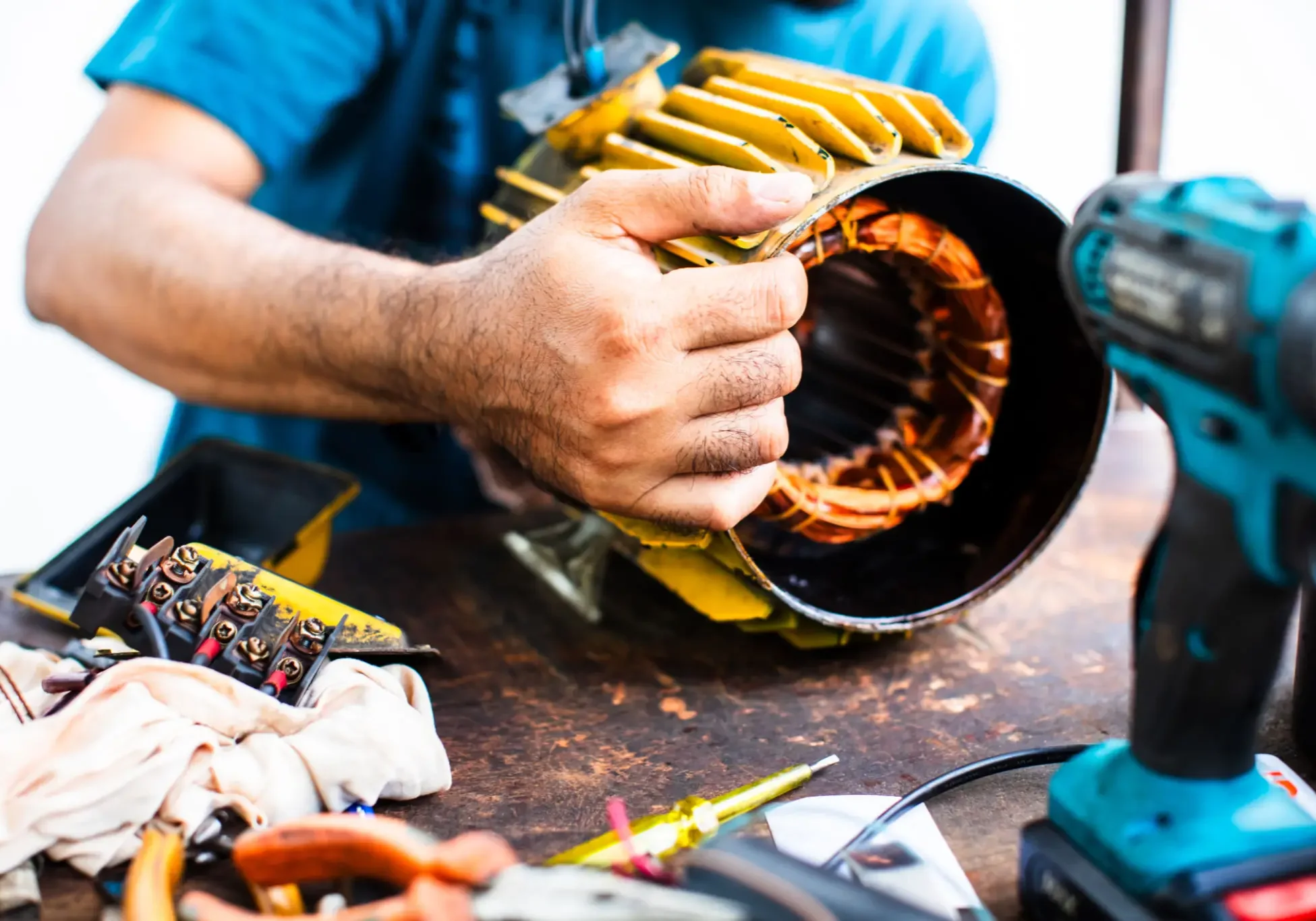 Person repairing motor with tools on table.